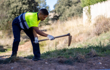 A young Hispanic male worker plowing soil in a park