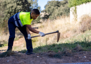A young Hispanic male worker plowing soil in a park
